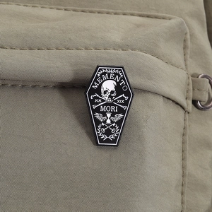 Macro shot of Memento Mori coffin enamel pin with gothic skull on green canvas