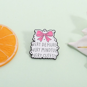 Pink bow enamel pin with Very Demure Very Mindful text for clothes and bags