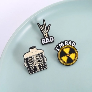 Three gothic enamel pins featuring skull, X-ray ribcage and radioactive hazard symbols