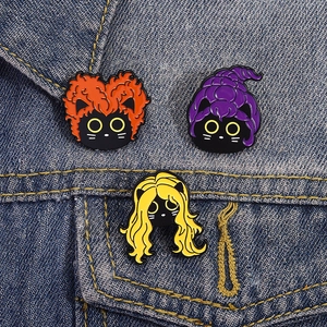 Détail de trois épingles en émail chat noir avec cheveux colorés sur une veste