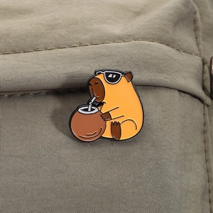 Détail d'un pin's en émail capybara avec lunettes de soleil sur tissu vert
