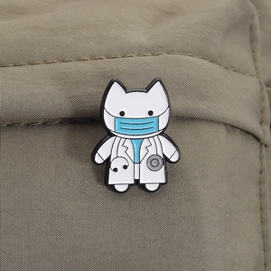 Detail of cartoon white cat doctor enamel pin with stethoscope on khaki fabric