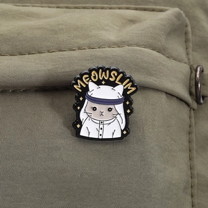 Close-up of cartoon Muslim cat enamel pin with Meowslim text on green nylon bag