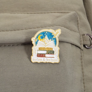 Pin's en émail livre avec dragons et montagnes sur sac à dos marron pour lecteur