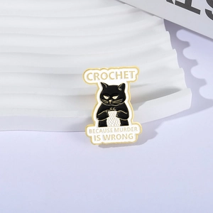 Black cat enamel brooch with 'Crochet because murder is wrong' text on white background
