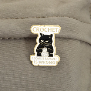 Detail of black cat enamel pin knitting with text Crochet Because Murder Is Wrong
