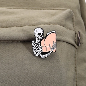 Detail of funny skeleton touching a buttocks enamel pin on a green nylon bag