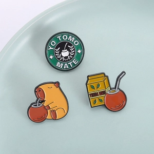 Three-piece enamel pins set featuring a cute capybara and mate tea theme on a ceramic plate