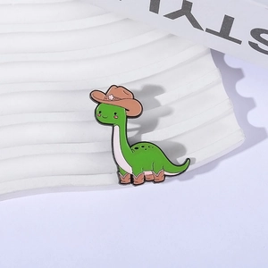 Cute green dinosaur enamel pin wearing a brown cowboy hat and boots, metal badge accessory