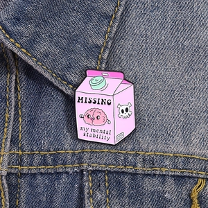 Detailansicht der rosa Milchkarton-Emaille-Anstecknadel auf einer Denim-Jacke