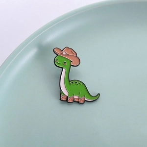 Emaille-Pin mit grünem Cartoon-Dinosaurier, Cowboyhut und Stiefeln auf einer Keramikschale
