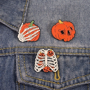 Set di spille smaltate di Halloween con teschi zucca e costole su giacca di jeans