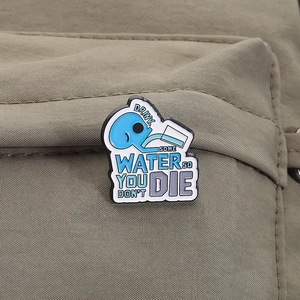 Detail of blue hydration enamel pin with quote Drink Some Water on a green backpack