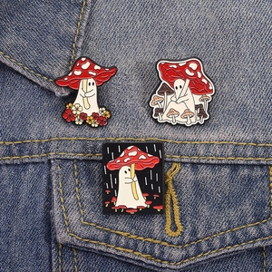 Three cute ghost and mushroom enamel pins on a denim jacket pocket and collar