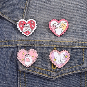 Pink heart-shaped enamel pins featuring cute cats and moon flower motifs on denim