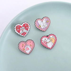 Set of four cartoon cat heart-shaped enamel pins with lace borders on a ceramic plate