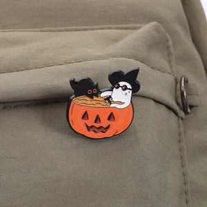 Cute Halloween enamel pin featuring a ghost, pumpkin and black cat on green fabric