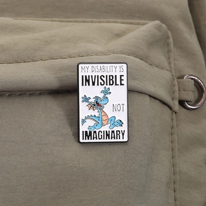 Macro view of blue dragon enamel pin featuring My Disability is Invisible text on bag