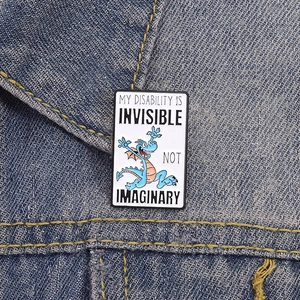 Rectangle enamel pin with a blue cartoon dragon and slogan on denim jacket
