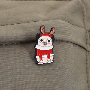 Makro-Detail einer Cartoon-Mops-Emaille-Anstecknadel mit Weihnachtsmütze auf Segeltuch