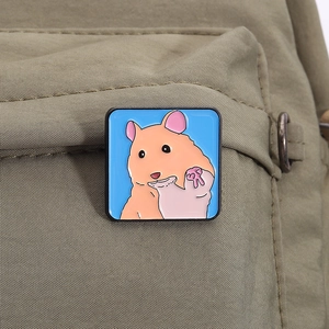 Gros plan d'un pin's en émail de hamster mignon sur la sangle d'un sac en toile verte