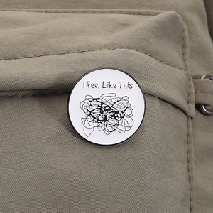 Gros plan du pin's en émail blanc avec texte sur un sac à dos en toile de couleur kaki