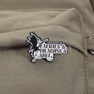Detail of dark fantasy enamel pin with silhouette and text on a green backpack