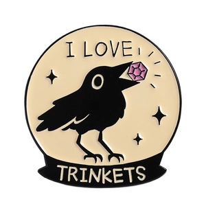 Enamel crow brooch with I LOVE TRINKETS text and purple gemstone on yellow background