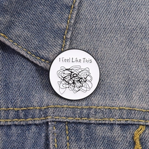 Détail de la broche artistique avec texte 'I feel Like This' sur veste en jean bleue