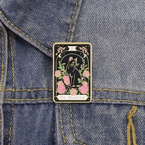 Detail of The Black Cat tarot enamel pin with pink roses on a blue denim jacket
