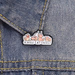 Gros plan d'une épingle en émail de chat orange fixée sur une veste en jean bleu marine