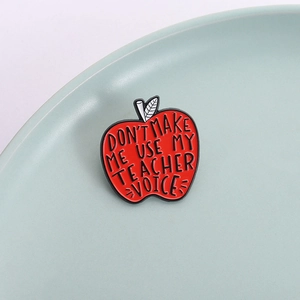 Red apple enamel pin for teachers featuring DON'T MAKE ME USE MY TEACHER VOICE text
