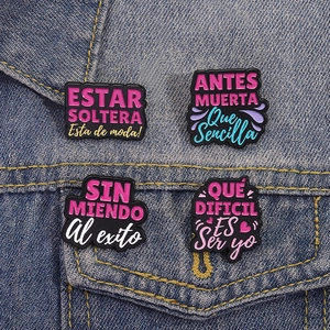Set of four colorful enamel lapel pins with Spanish quotes on blue denim jacket