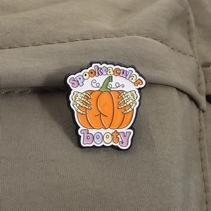 Detail of Halloween pumpkin booty enamel pin with skeleton hand on a canvas bag