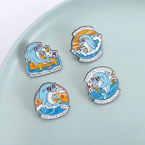 Set of four cute dolphin enamel pins with summer beach and surfing motifs in blue and orange