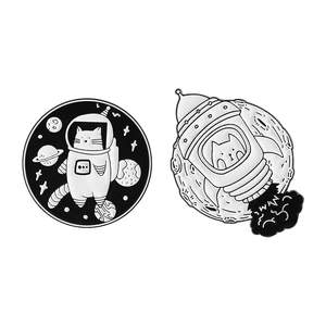 Set of 2 monochrome space cat enamel pins featuring a floating astronaut and rocket cat