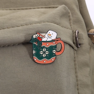 Detailed view of Christmas enamel pin featuring a marshmallow snowman on a canvas bag