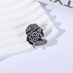 Black enamel inspirational quote pin with white motivational text on a wavy display