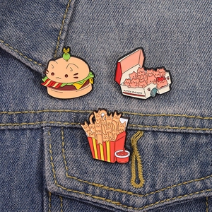 Three creative enamel cat burger and kitten nuggets pins on blue denim jacket