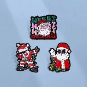 Three assorted Christmas Santa Claus enamel pins on a light blue background