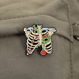 Macro detail of Christmas skeleton ribcage enamel pin with candy canes and holly berries