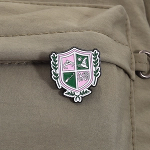 Detail of magic themed shield enamel pin pinned on an olive green textured fabric bag