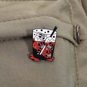Detail of dark skull beverage enamel pin on khaki canvas texture fabric material