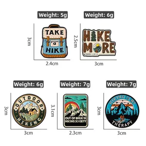 Detail of five outdoor adventure enamel pins featuring mountain and hiking designs