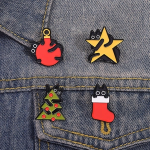 Set di quattro spille smaltate gatto nero di Natale con albero e stella su giacca di jeans