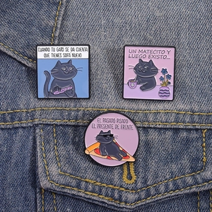 Detail of funny black cat enamel pins on denim jacket showing pizza and tea scenes