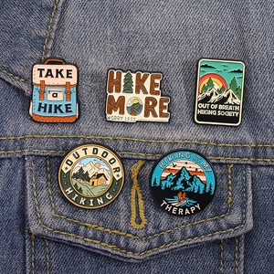 Set of 5 outdoor hiking enamel pins featuring mountain forest designs on denim jacket