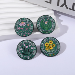 Set of four floral enamel pins with Spanish slogans on a white wavy stand for bags
