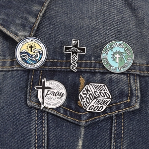 Vue détaillée de pins religieux en émail avec croix et motifs marins sur veste en jean