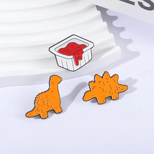 Cartoon enamel pin set with dinosaur chicken nuggets and a red tomato sauce dip box